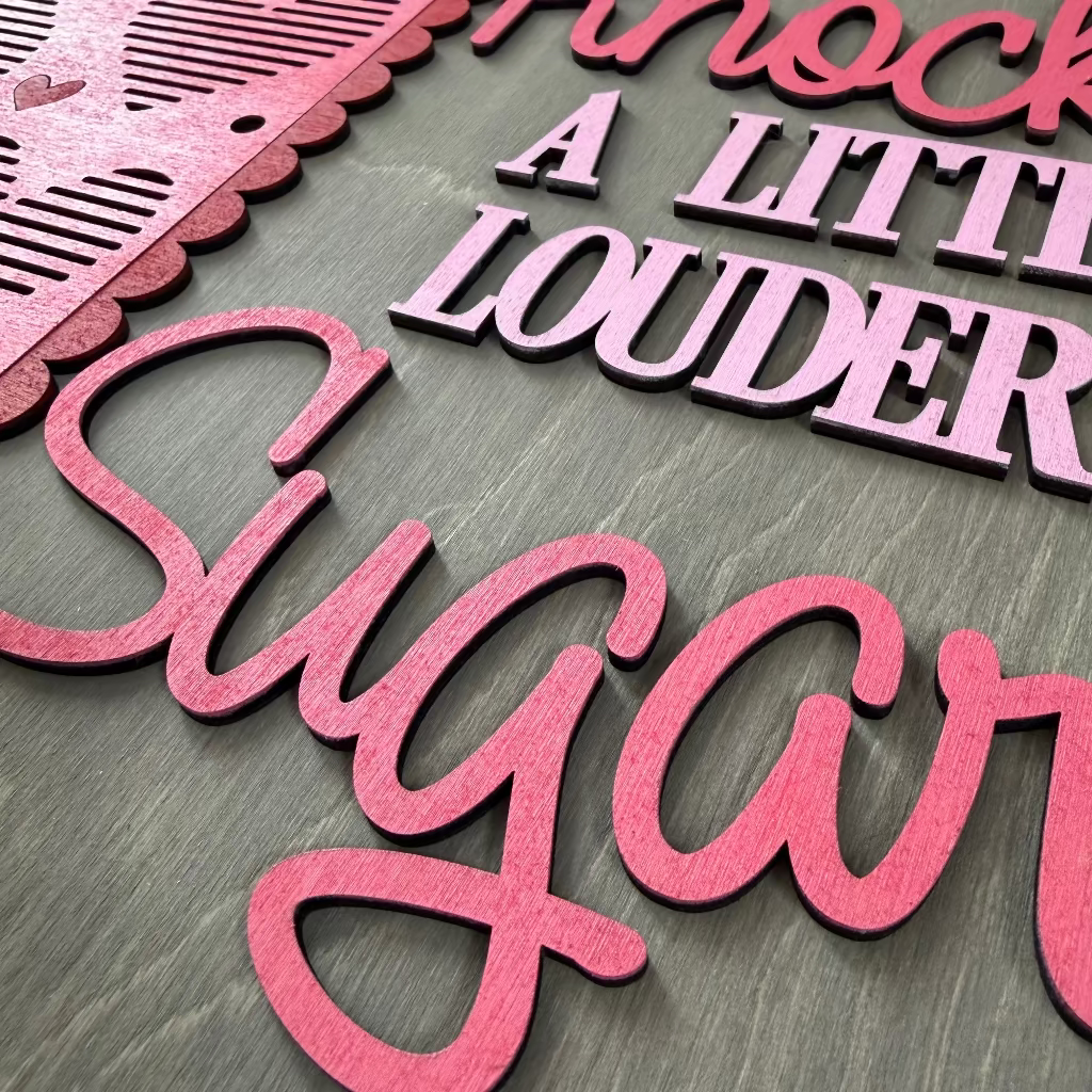Decorative sign with 'Knock A Little Louder Sugar' text on a pink and gray background with heart shapes.