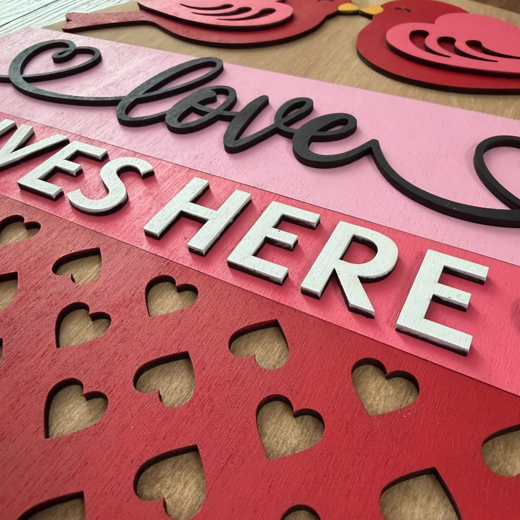 3D wooden sign with 'Love Lives Here' text and heart shapes on a wooden surface.