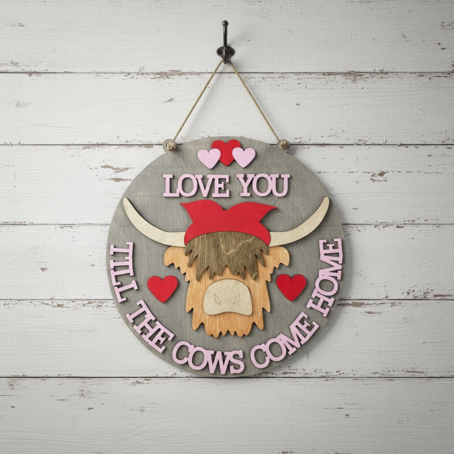 Decorative sign with a highland cow head and text 'Love you till the cows come home' on a 3D wooden background.