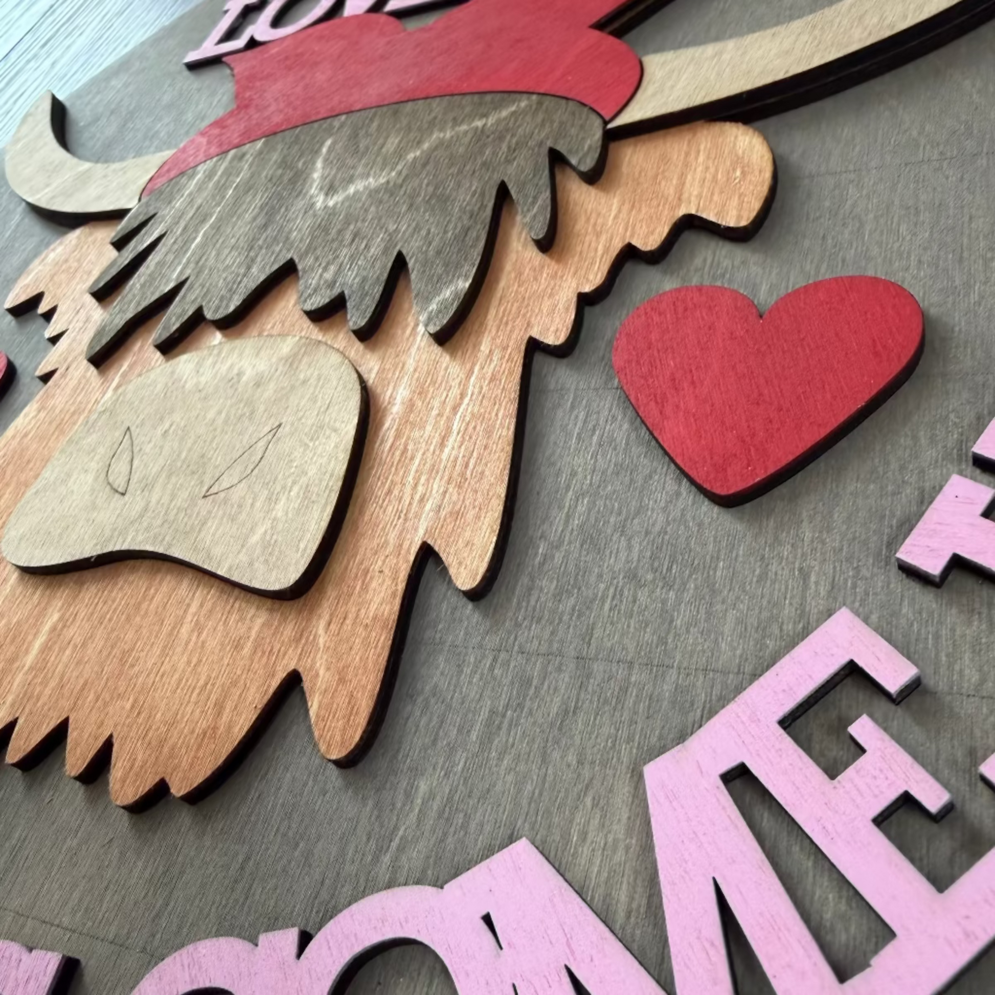 Decorative sign with a highland cow head and text 'Love you till the cows come home' on a 3D wooden background.