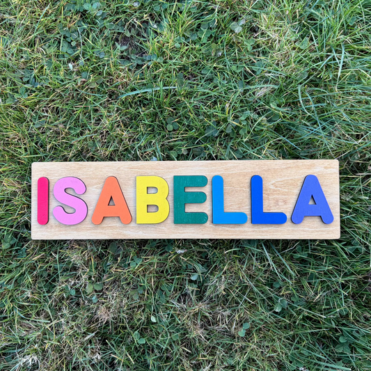 Wooden name puzzle with colorful letters spelling 'ISABELLA' on grass