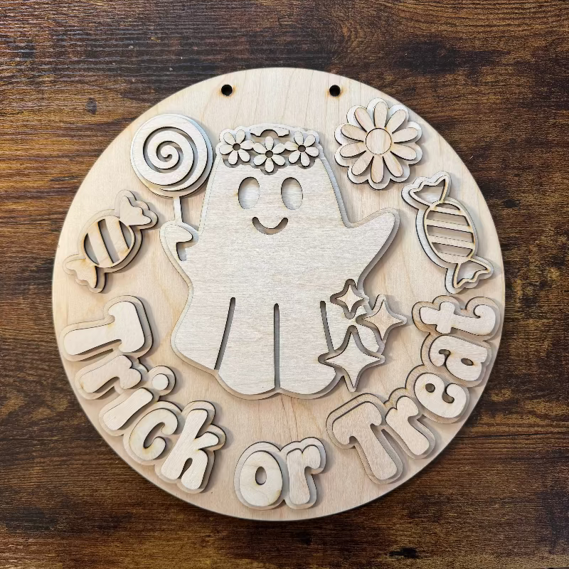 Round wooden sign with a ghost eating candy saying "Trick or Treat"